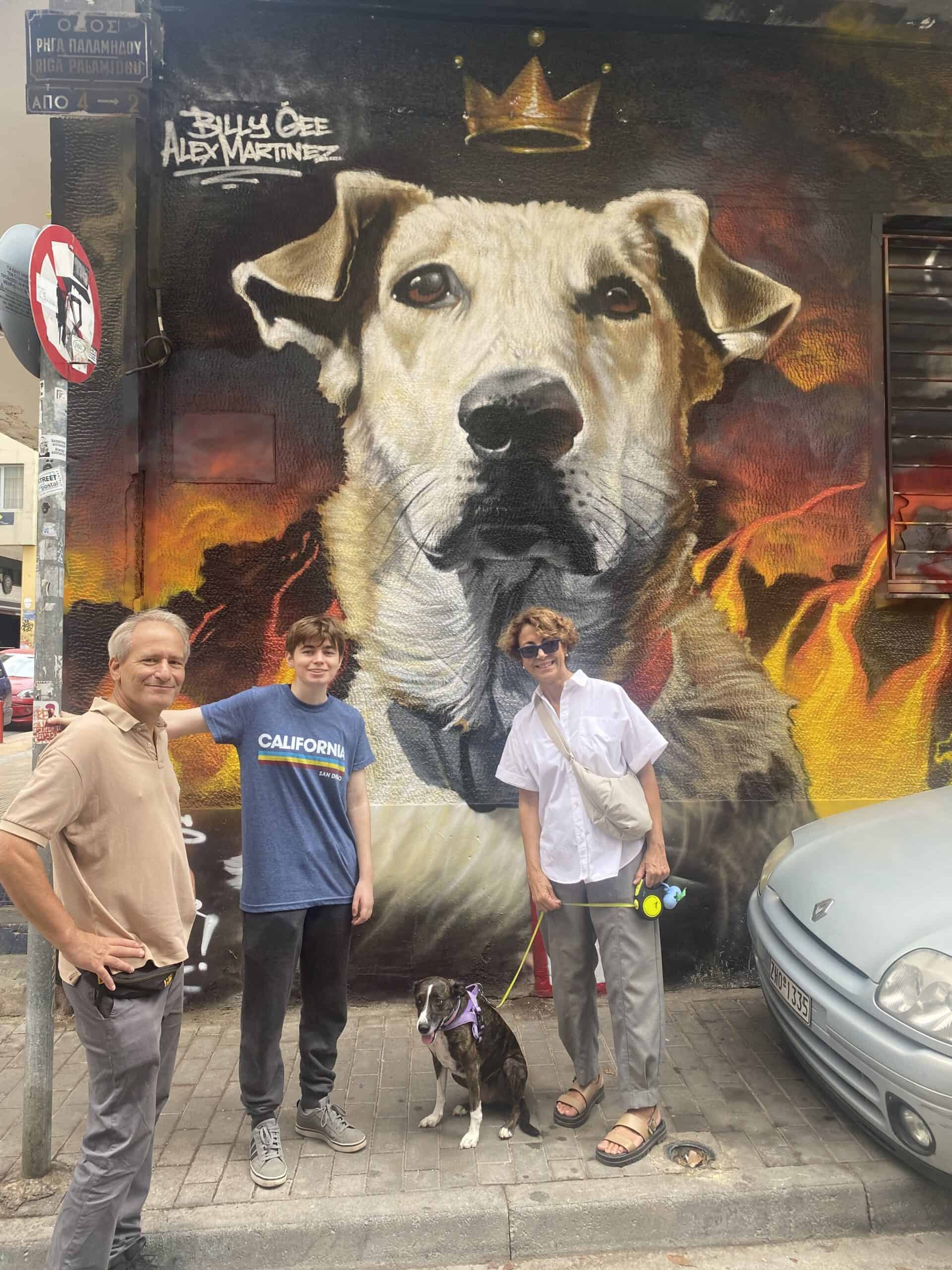 Large street art mural of a crowned dog with flames, by Billy Gee Alex Martinez, with three people and a leashed dog.